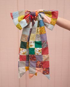 someone is holding up a colorful patchwork scarf