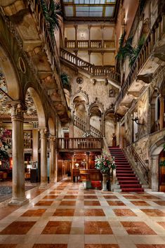 an ornate lobby with stairs and potted plants