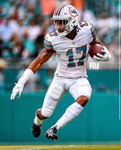 a football player running with the ball in his hand and people watching from the stands