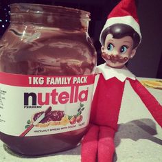 an elf is sitting next to a jar of nutella