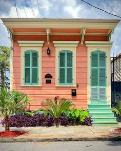 a pink house with green shutters on the front