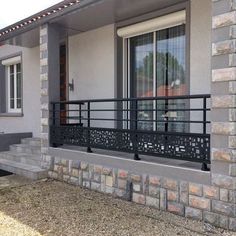 a house with stone and metal railings in front of the door, windows on both sides