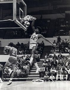 an old black and white photo of a basketball player jumping up to dunk the ball