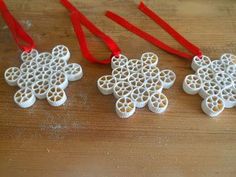 three white ornaments with red ribbons hanging from them on a wooden table next to each other