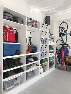 a room filled with lots of white shelves next to a bike and bins on the wall