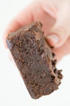 a hand holding a piece of brownie in it's left hand with chocolate chips on top