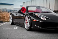 a black sports car parked in front of a building with red leather seat covers on it