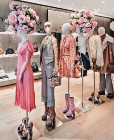 several mannequins dressed in dresses and shoes with flowers on display behind them