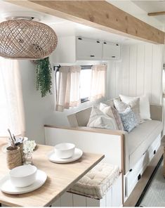 the interior of a camper with white furniture and pillows on it's back