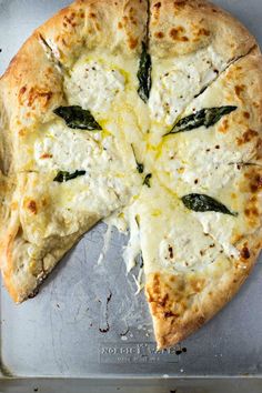 a pizza with cheese and spinach on it sitting on top of a metal pan