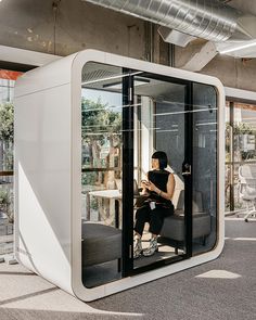 a woman sitting on a chair in a room with glass walls