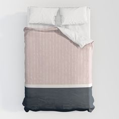 a bed with two pillows and a pink comforter on top of it, in front of a white wall