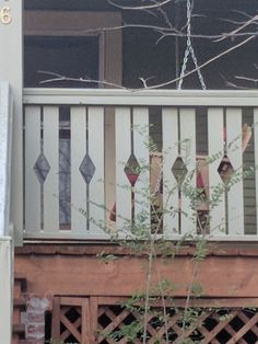 a cat sitting on top of a wooden porch next to a tree and fence with no leaves