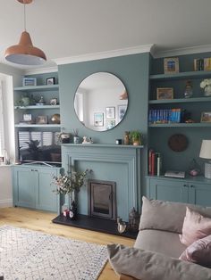 a living room filled with furniture and a fire place under a round mirror on the wall