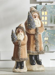 two statues of santa claus and snowman in front of a christmas tree with lights