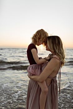 two women are hugging on the beach at sunset