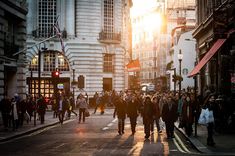 many people are walking down the street at sunset