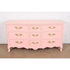 a pink dresser with gold trim and drawers