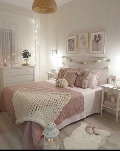 a bedroom decorated in pink and white with lights on the headboard, rugs and bedding