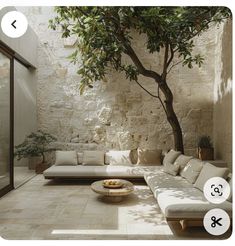 a living room filled with white furniture and a tree in the middle of the room