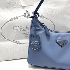 a blue prada bag sitting on top of a white table next to a pillow