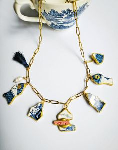 a blue and white porcelain necklace on a table next to a teacup with a cup in the background