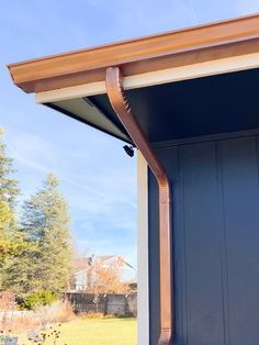 an outside view of a house with a blue door and brown gutter on the side