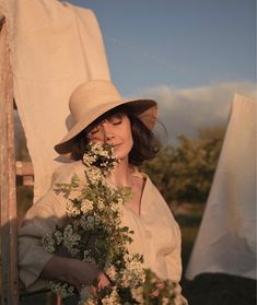 a woman wearing a hat and holding flowers