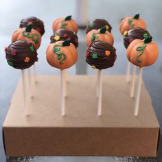 chocolate covered pumpkins sitting on top of wooden sticks with green and orange decorations around them