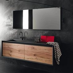 a bathroom with black and white walls, wooden cabinets and a large mirror on the wall