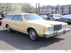 an old yellow station wagon parked in a parking lot