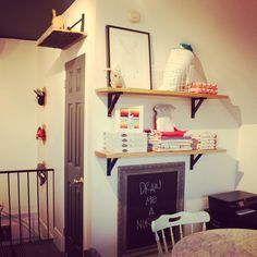 a room with some shelves on the wall and a chalkboard in front of it