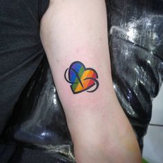 a woman's arm with a colorful heart tattoo on the left side of her arm