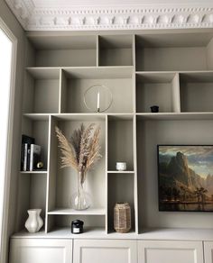 a white bookcase filled with books and vases