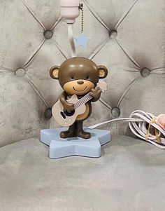 a brown teddy bear holding a guitar on a blue stand next to a white string