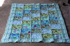 a blue and green baby quilt laying on the floor