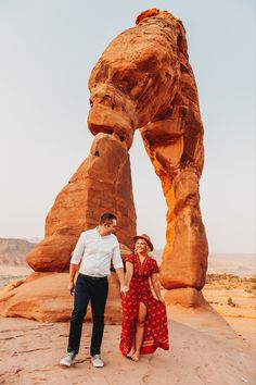 a man and woman standing in front of a rock formation