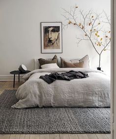 a bedroom with white walls and wood flooring has a large bed in the middle