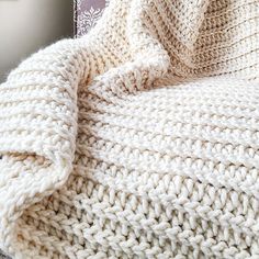 a white knitted blanket sitting on top of a chair