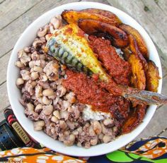 a white bowl filled with lots of food on top of a wooden table