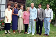 a group of people standing next to each other in front of a building and trees