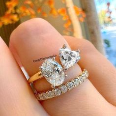 two diamond engagement rings on top of each other in front of an orange tree with leaves