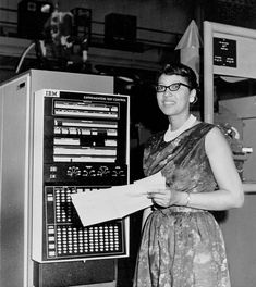 an old photo of a woman standing in front of a machine with papers on it