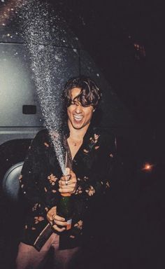 a woman standing under an umbrella and spraying water on her face while holding a bottle