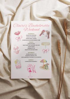 a pink and white menu sitting on top of a bed next to some dry grass