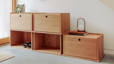 a wooden shelf with two drawers next to a window and a rug on the floor