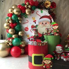 an assortment of christmas decorations on display in front of a wall with balloons and garlands