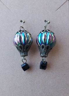 a pair of silver and black earrings on top of a white surface with beads hanging from it's sides