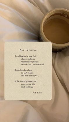 a cup of coffee sitting on top of a bed next to a paper with an inscription