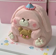 a cake shaped like a pink dog with a birthday hat on its head and paws